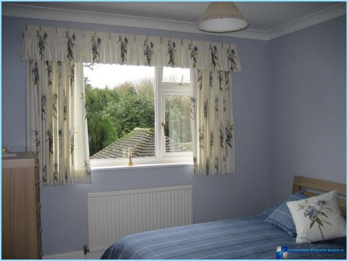 Short curtains to the window sill in the bedroom interior